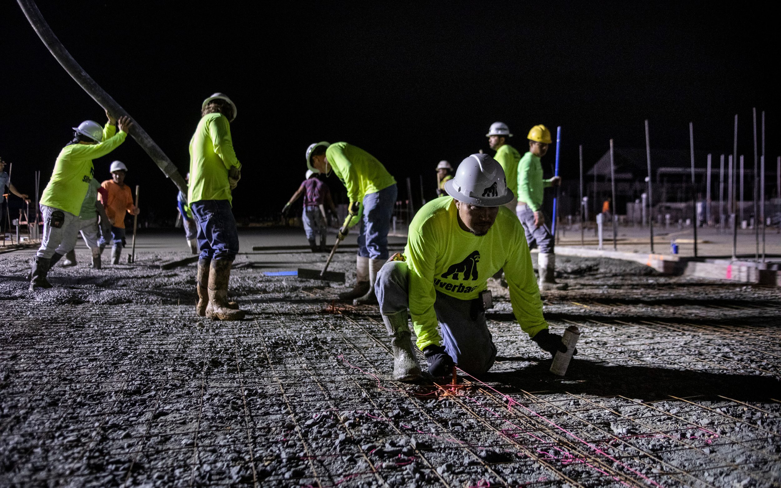 Construction site, workers at night under generator lights.